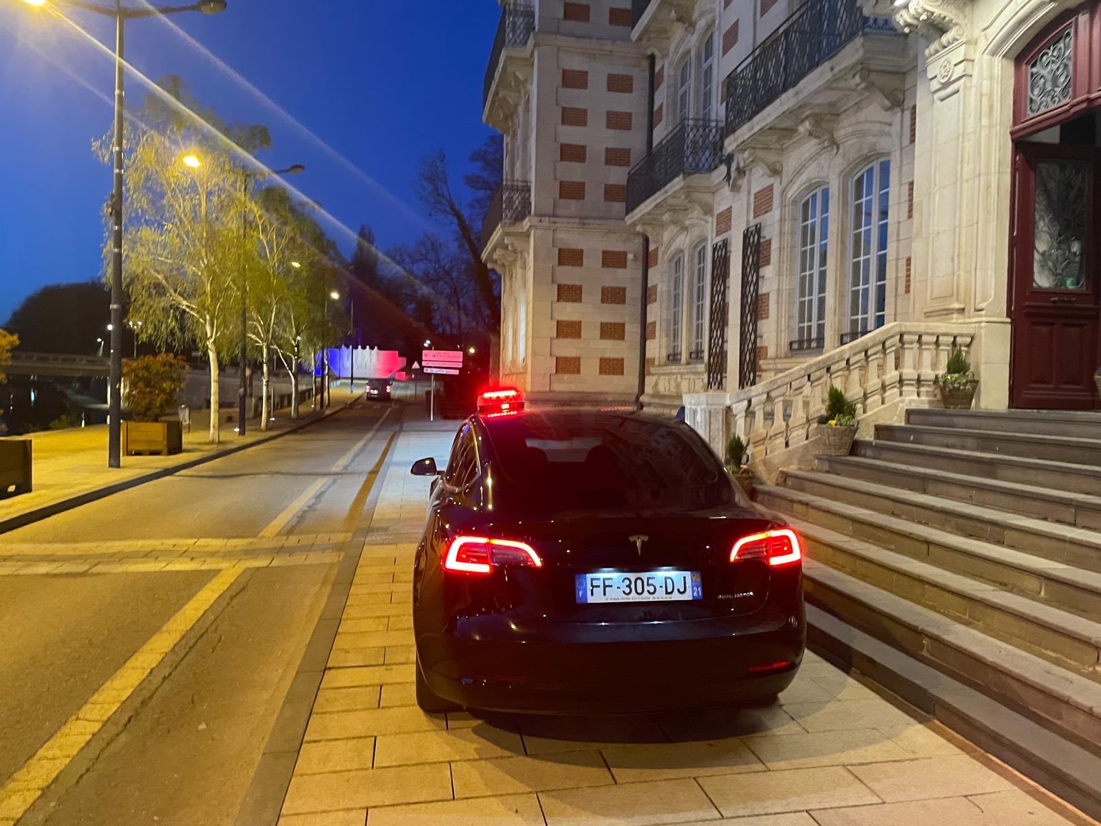 Tesla noire de nuit devant un hôtel à Verdun